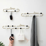 White wall-mounted coat rack with hooks and storage shelf