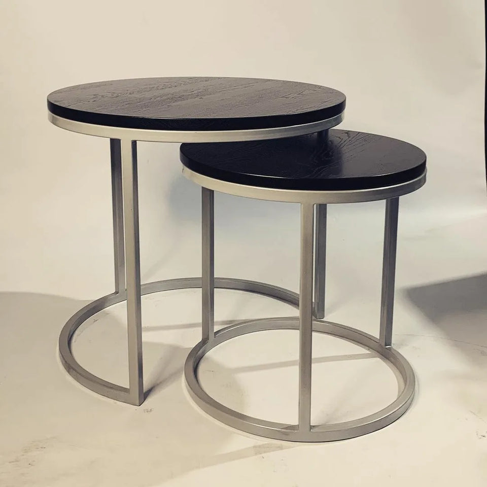 Set of modern round nesting coffee tables with black wood tops and silver metal bases.