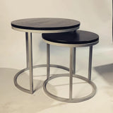 Set of modern round nesting coffee tables with black wood tops and silver metal bases.